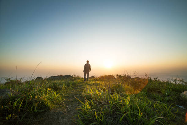 man walking near sunset on top of mountain stock photo