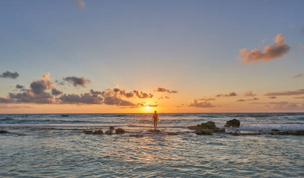 Man Walking on a Sandbar during Sunrise Over the Caribbean Sea on Cozumel Island off the Yucatan Peninsula of Mexico stock photo