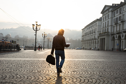 Man walks down cobblestone street at sunrise