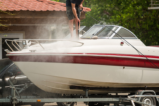 A man washes a motor yacht with a jet of water at a boat station, close-up