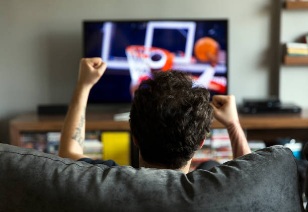 Man watching basketball on tv stock photo