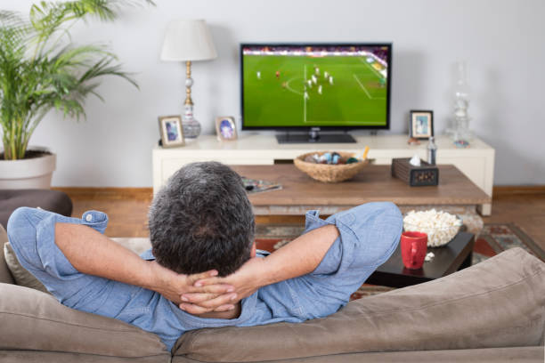 hombre viendo partido de fútbol en casa - televisión fotografías e imágenes de stock