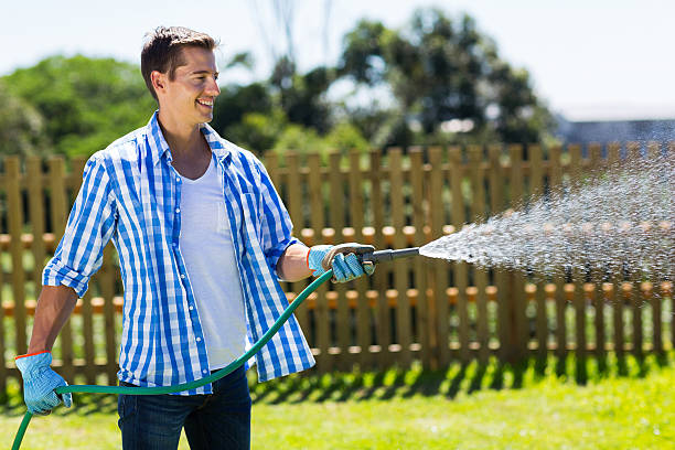 man watering garden cheerful man watering home garden garden hose stock pictures, royalty-free photos & images