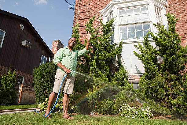 Man watering grass with hosepipe  front yard stock pictures, royalty-free photos & images