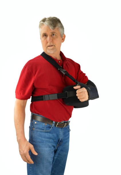 Man wearing a shoulder surgery sling with abduction pillow during recovery and healing stock photo