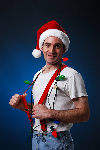 Man wearing Christmas hat, lights, and red suspenders stock photo