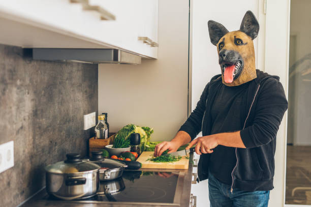 Man wearing dog mask cooking vegetables in the kitchen