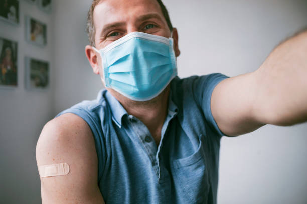 Man wearing protective face mask taking a selfie after vaccination against Covid-19 stock photo