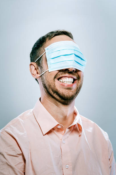 남자는 입 대신 그의 눈 위에 보호 얼굴 마스크를 착용 - 부주의한 뉴스 사진 이미지