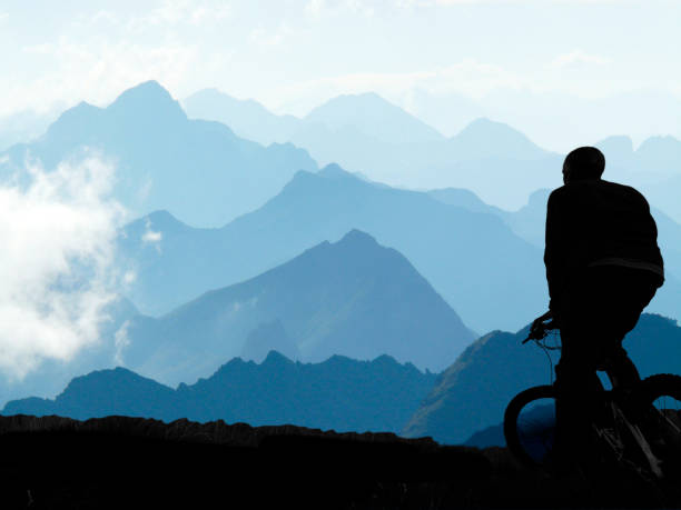 Man with a mountain bike in front of the landscape of a mountain range stock photo
