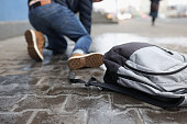 istock Man with backpack felling on slippery sidewalk in winter closeup 1322089117