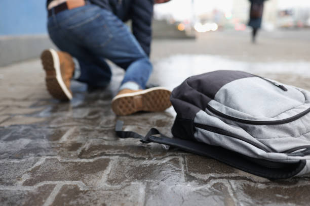Man with backpack felling on slippery sidewalk in winter closeup stock photo