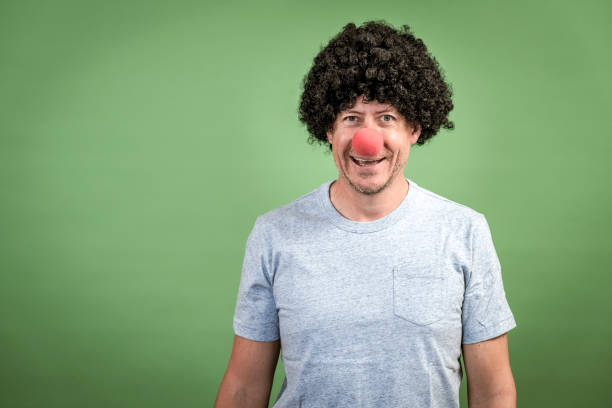 Man with black wig and red clown nose stock photo