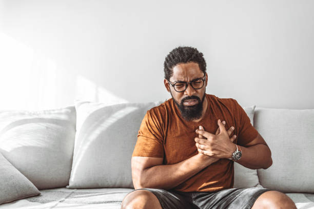 Man with chest pains Man with chest pain suffering from heart attack while sitting at home during the day. chest pain stock pictures, royalty-free photos & images