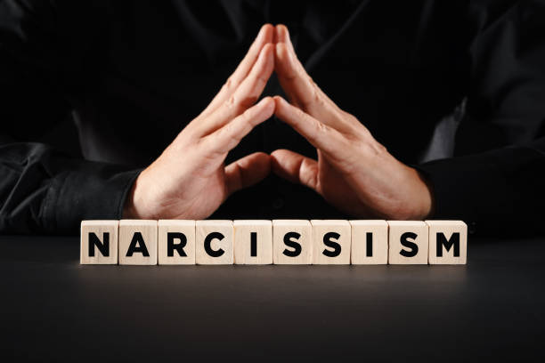 Man with clasped hands with the word narcissism. Personal ego or selfishness concept. stock photo