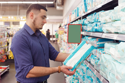 man with diaper pack in supermarket, reading information