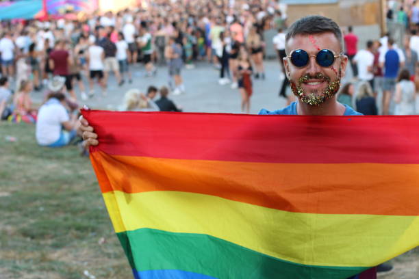 hombre con barba de brillo con la bandera del arco iris - nyc pride parade fotografías e imágenes de stock