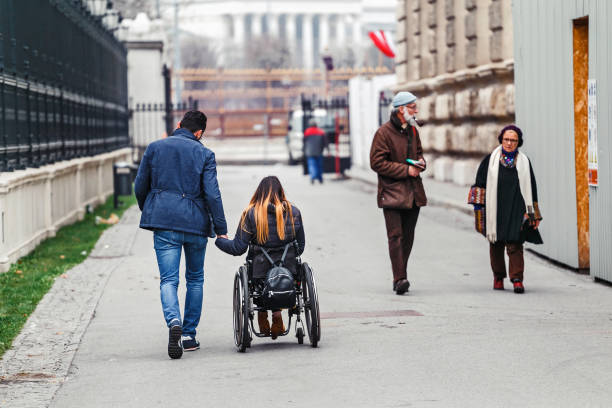 a man with his beloved disabled girlfriend on a wheelchair is traveling around the city of vienna in austria, view from the back. - wheelchair street imagens e fotografias de stock