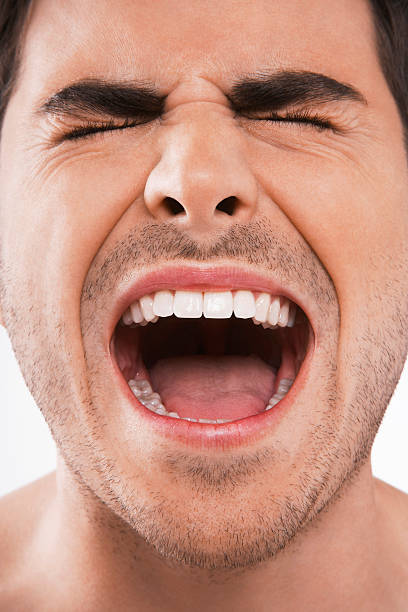 Man with his eyes closed screaming loudly Closeup of young man screaming with eyes closed on white background mouth open stock pictures, royalty-free photos & images