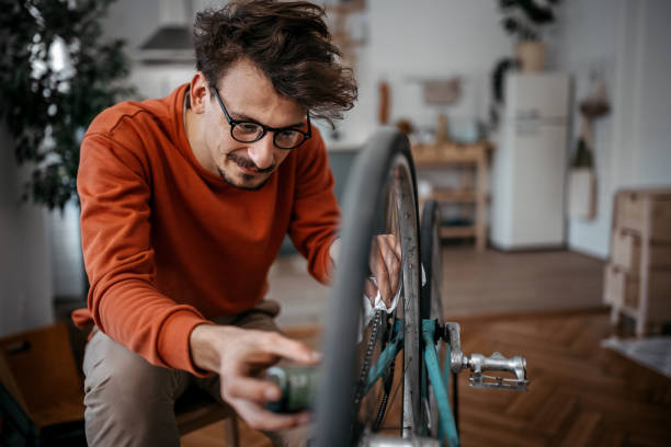 man with motor oil repairing bicycle at home - apart raderen broken stockfoto's en -beelden