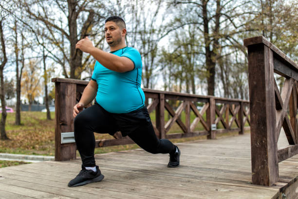 Man with overweight problem exercising in city park Plus size man training and running outdoors. He is doing some cardio exercises for weight loss after quarantine period obesity stock pictures, royalty-free photos & images