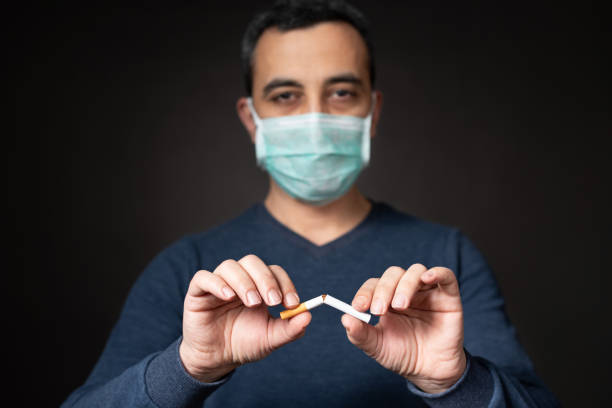 covid-19 후 담배를 깨는 보호 얼굴 마스크와 남자, 금연 개념 - 니코틴 뉴스 사진 이미지