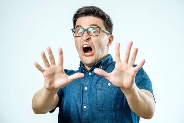Man with scared expression on his face making frightened gesture with his palms as if trying to defend himself from someone stock photo
