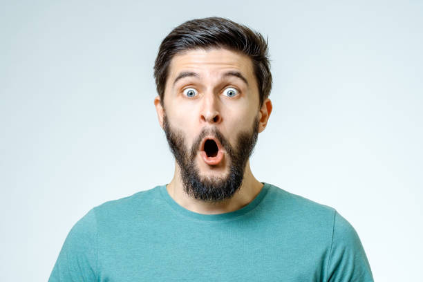 Man with shocked, amazed expression isolated on gray background stock photo
