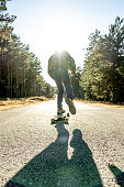 istock man with skating down a lonely road against the sun 1421491769