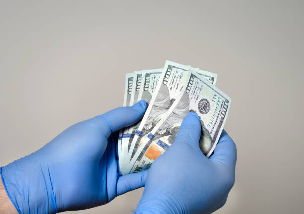 Man with surgical gloves on his hand counting the dollars  money bancknotes  .Protection against contamination with covid-19 and bacteria Man with surgical gloves on his hand counting the dollars  money bancknotes  .Protection against contamination with covid-19 and bacteria economic stimulus stock pictures, royalty-free photos & images