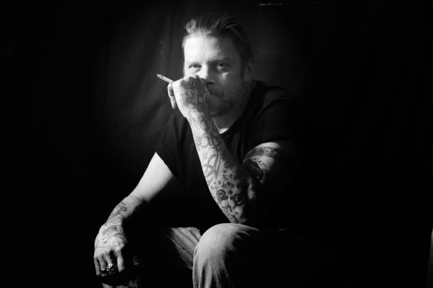 Man With Tattoos Smoking a Cigarette Black and White stock photo