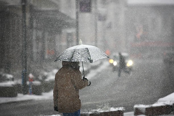 man with umbrella during snow storm - lichte sneeuw stockfoto's en -beelden