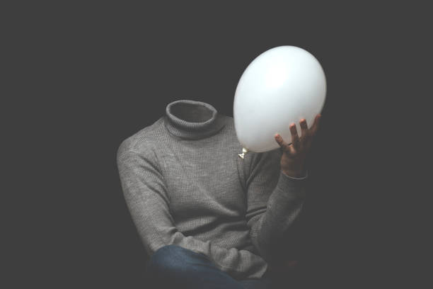 man without head pressing white balloon stock photo