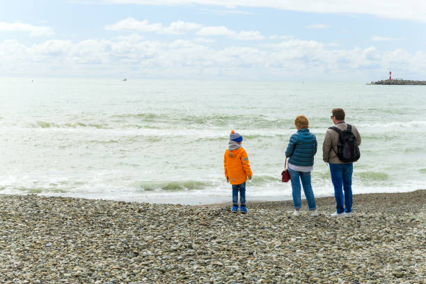 SOCHI,RUSSIA,  20 APRIL 2019 - man, woman and their child stand with backs to the camera on the Black sea shore in cloudy weathe man, woman and their child stand with backs to the camera on the Black sea shore in cloudy weather divorce beach stock pictures, royalty-free photos & images