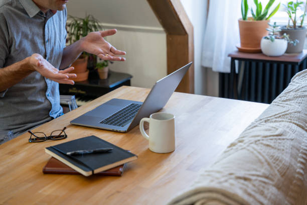Man working from home on a video call on his laptop. stock photo