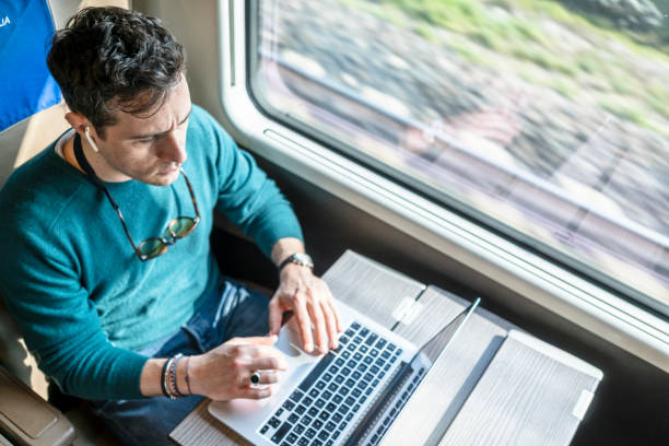Man working on train with laptop stock photo