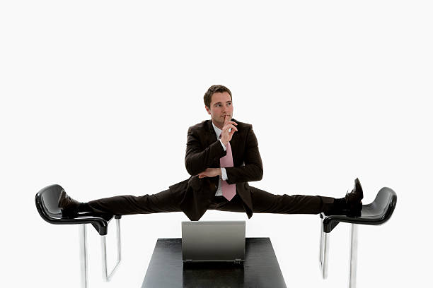 Manager doing a split between two black chairs in a suit Manager doing the splits between two chairs. doing the splits stock pictures, royalty-free photos & images