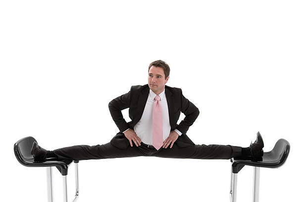 Manager is caught between two chairs Manager doing the splits between two chairs.Oftly an uncomfortable situation in office. doing the splits stock pictures, royalty-free photos & images