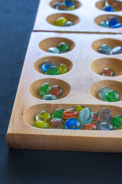Mancala board and marbles on black background stock photo