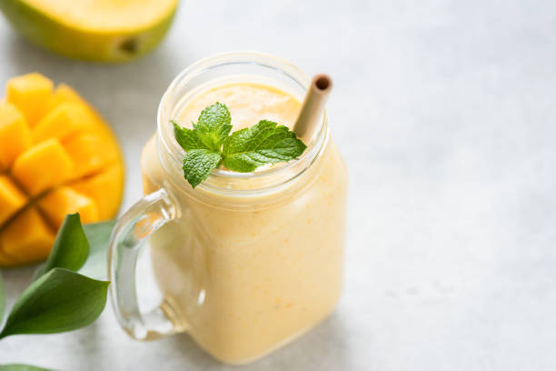 Mango lassi in a glass jar Mango lassi in a glass on grey concrete background table, copy space for text or design. Mango yogurt smoothie mango smoothie stock pictures, royalty-free photos & images