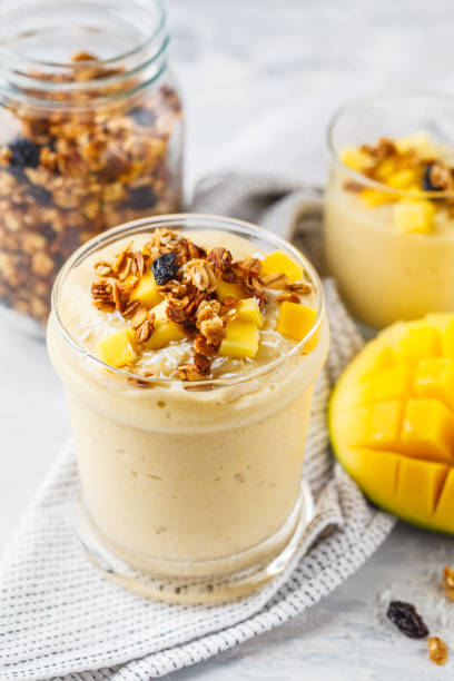 Mango smoothie with granola and coconut in a jar. Mango smoothie with granola and coconut in a jar. Healthy vegan food concept. mango smoothie stock pictures, royalty-free photos & images