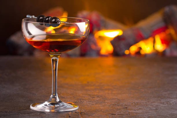 Manhattan cocktail on fireplace background A glass of classic Manhattan cocktail on fireplace background vermouth stock pictures, royalty-free photos & images
