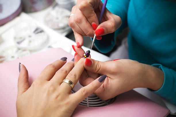 Manicure - Nail polish Beautician putting nail decoration, at the nail salon. nail salon stock pictures, royalty-free photos & images