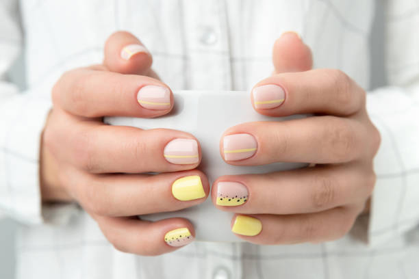 Manicured woman's hands holding a cup of coffee or tea Manicured woman's hands holding a cup of coffee or tea. Spring summer yellow manicure design close up nail polish stock pictures, royalty-free photos & images