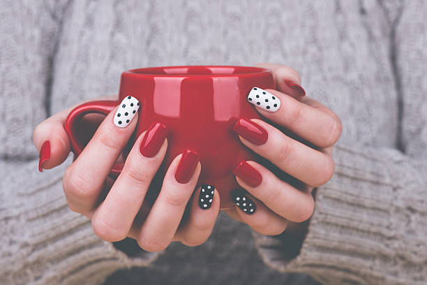 Manicured woman's hands holding cup Beauty treatment photo of nice manicured woman fingernails. Very nice feminine nail art with nice red, white and black nail polish. Processed in retro colors. nail salon stock pictures, royalty-free photos & images