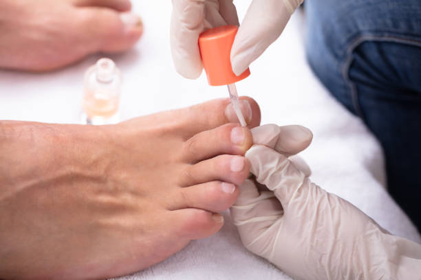 Manicurist Applying Moisturizing Nail Oil To Man's Feet Close-up Of Manicurist Hand Applying Moisturizing Nail Oil To Man's Feet man pedicure stock pictures, royalty-free photos & images