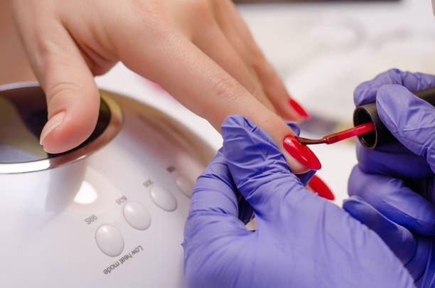 Manicurist in rubber gloves covering nails with red gel polish in the beauty salon. Perfect nails manicure process Closeup shot of master in rubber gloves covering nails with red gel polish in the beauty salon. Perfect nails manicure process gel nail polish stock pictures, royalty-free photos & images