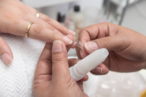 A manicurist places a clear nail extension to the finger. At a salon or parlor. stock photo