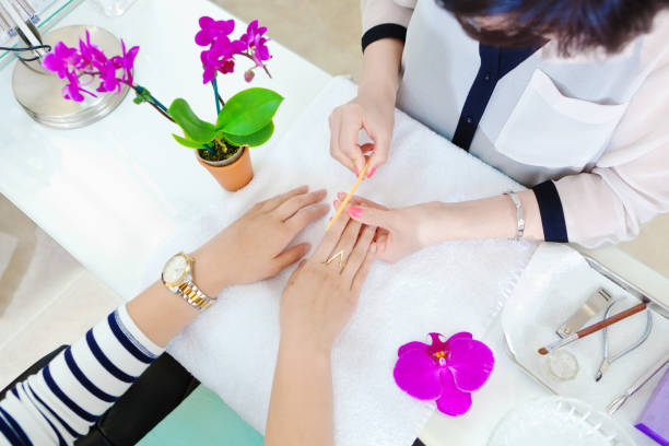 Manicurists and Pedicurists Serving Customers in Nail Spa Salon Manicure and pedicure salon serving Customer in a spa salon. An Asian owned small business in personal body care. A manicure in progress. manicure stock pictures, royalty-free photos & images