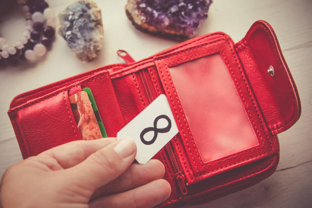 manifestando el concepto de dinero. vista de cerca de la mano de la persona mujer sosteniendo la billetera roja y el símbolo del infinito para atraer más riqueza y dinero. - feng shui wallet fotografías e imágenes de stock